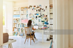 Rear view of pregnant woman sitting in home office and working on laptop